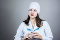 Doctor woman in white coat with dark hair in medical blue mask holds syringe in hands