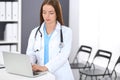 Doctor woman at work. Portrait of female physician using laptop computer while standing near reception desk at clinic or Royalty Free Stock Photo