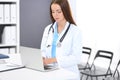 Doctor woman at work. Portrait of female physician using laptop computer while standing near reception desk at clinic or Royalty Free Stock Photo