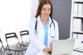 Doctor woman at work. Portrait of female physician using laptop computer while standing near reception desk at clinic or Royalty Free Stock Photo