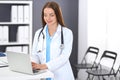 Doctor woman at work. Portrait of female physician using laptop computer while standing near reception desk at clinic or Royalty Free Stock Photo