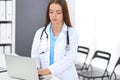 Doctor woman at work. Portrait of female physician using laptop computer while standing near reception desk at clinic or Royalty Free Stock Photo