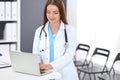 Doctor woman at work. Portrait of female physician using laptop computer while standing near reception desk at clinic or Royalty Free Stock Photo
