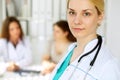 Doctor woman or nurse in a hospital office with her colleague and patient in the background. Healthcare and medicine Royalty Free Stock Photo