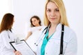 Doctor woman or nurse in a hospital office with her colleague and patient in the background. Healthcare and medicine Royalty Free Stock Photo