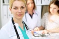 Doctor woman or nurse in a hospital office with her colleague and patient in the background. Healthcare and medicine Royalty Free Stock Photo