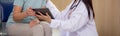 Doctor woman and senior patient talking and looking on tablet computer for diagnostics and examining disease at hospital. Royalty Free Stock Photo