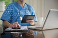 Doctor working on laptop computer and tablet and medical stethoscope on clipboard on desk, electronics medical record system EMRs Royalty Free Stock Photo