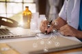 Doctor working on laptop computer, writing prescription clipboard with record information.