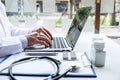 Doctor working with laptop in hospital and medical stethoscope, medicine on clipboard on desk Royalty Free Stock Photo