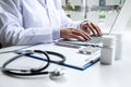 Doctor working with laptop in hospital and medical stethoscope, medicine on clipboard on desk Royalty Free Stock Photo