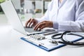 Doctor working with laptop in hospital and medical stethoscope, medicine on clipboard on desk Royalty Free Stock Photo