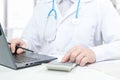 Doctor working with medical statistics and financial reports. doctor counts on calculator and enters data into laptop. male doctor Royalty Free Stock Photo