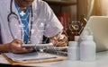 Doctor working with tablet and writing on paperwork. Royalty Free Stock Photo
