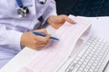 Doctor workplace. Electrocardiogram, ecg in hand of a female doctor with ekg graph paper in hospital office room with computer,