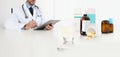 Doctor writes the medical prescription with the digital tablet on a desk office with glass, aspirin and drugs, cold and flu cure