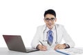 Doctor writes a prescription and looking at camera Royalty Free Stock Photo