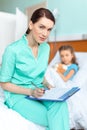 Doctor writing in clipboard diagnosis of sick little girl