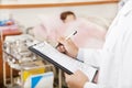 Doctor writing on a medical chart with patient Royalty Free Stock Photo