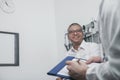 Doctor writing on medical chart with a smiling patient Royalty Free Stock Photo