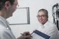 Doctor writing on medical chart with a smiling patient