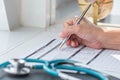Doctor writing on medical health care record, patients discharge, or prescription form paperwork in hospital clinic office Royalty Free Stock Photo