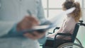 Doctor writing medical records and patient in a wheelchair Royalty Free Stock Photo