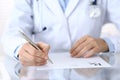 Doctor writing prescription form while sitting at glass desk in hospital, closeup view. Healthcare, insurance an Royalty Free Stock Photo