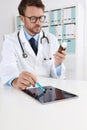 Doctor writing prescription in medical office with drugs touch digital tablet on desk Royalty Free Stock Photo