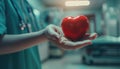 Doctor's hand holding a red heart shape in a hospital. love, donor, world heart day by AI generated image Royalty Free Stock Photo