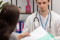 A young patient takes lab results out of her folder. Primary care physician. Doctor's office