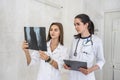 Doctor with young intern analyzing patient`s x-ray in hospital. One woman holding and and they both looking on it Royalty Free Stock Photo