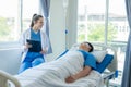 Doctor and young male patient lying in bed while checking pulse Consult Royalty Free Stock Photo