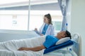 Doctor and young male patient lying in bed while checking pulse Consult Royalty Free Stock Photo