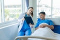 Doctor and young male patient lying in bed while checking pulse Consult Royalty Free Stock Photo