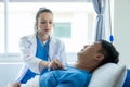 Doctor and young male patient lying in bed while checking pulse Consult Royalty Free Stock Photo