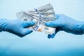 Doctors in blue gloves holds money cash dollars on blue background. Concept of bribe, corruption, profitshare or illegal Royalty Free Stock Photo