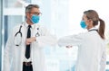 Doctors doing covid safe greeting with elbow, wearing face mask to protect from virus and working in a hospital Royalty Free Stock Photo