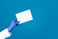 Doctors hand in a glove holds an envelope on a blue background with copy space Royalty Free Stock Photo