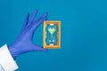 Doctors hand in a glove holds an hourglass on a blue background with copy space
