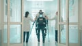 Doctors are helping male patient to walk in the exosuit