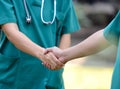 Doctors in a medical team handshake together outdoor on the green park background (volunteer) Royalty Free Stock Photo