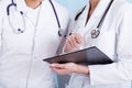 Doctors in medical white apron with stethoscopes and clipboard