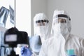 Doctors in protective screens and anti-plague suits looking into camera in X-ray room Royalty Free Stock Photo