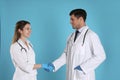 Doctors shaking hands on light blue background