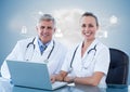 Doctors using laptop at desk against digitally generated background Royalty Free Stock Photo