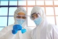 Doctors in virus protective suit working in lab looking the example in glass bottle Royalty Free Stock Photo