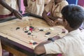 Documentary editorial image. Children playing carrom at the table. the concept of childhood and board games, brain development and