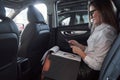 Documents in the notepad. Smart businesswoman sits at backseat of the luxury car with black interior