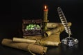 Documents in scrolls, a burning candle, an old book, a chest with jewelry on a black background Royalty Free Stock Photo